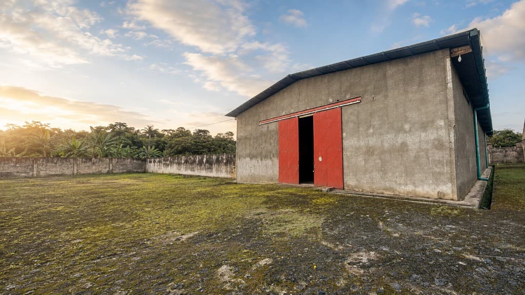 Façade de l'usine et entrepôt SAMEN INDUSTRY au Cameroun, porte rouge au coucher du soleil